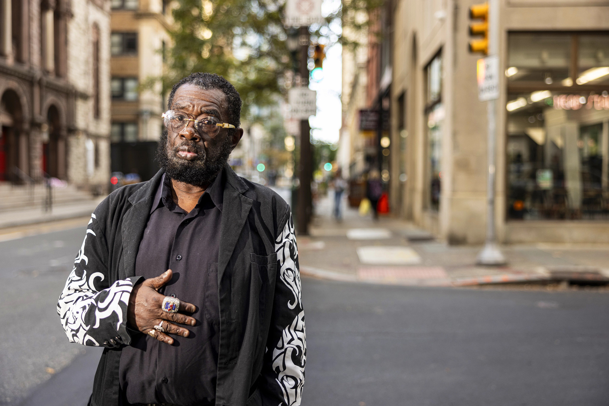 a man in a black shirt and glasses looks at the camera