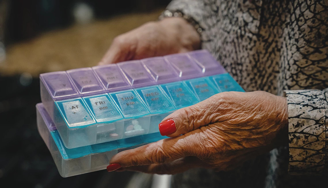 deanna brandt holds the pill organizer holding her medications.