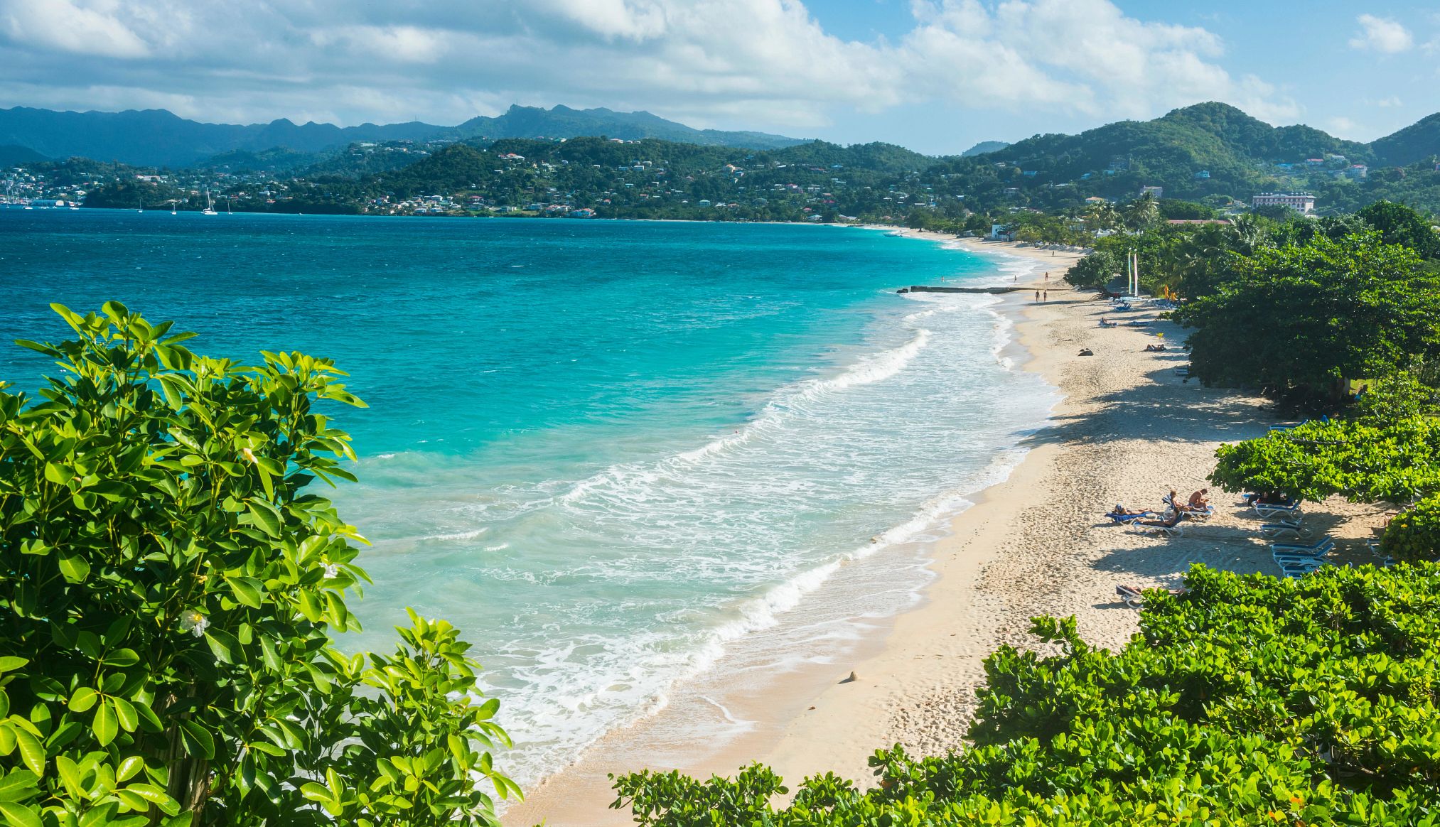 Quiet Caribbean Beaches a long stretch of beach with a few beachgoers scattered along the sand
