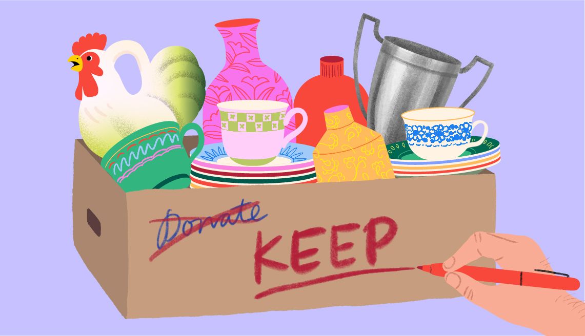 Decluttering Duels a cardboard box with household items in it. the word donate is crossed off as a hand writes keep on the box