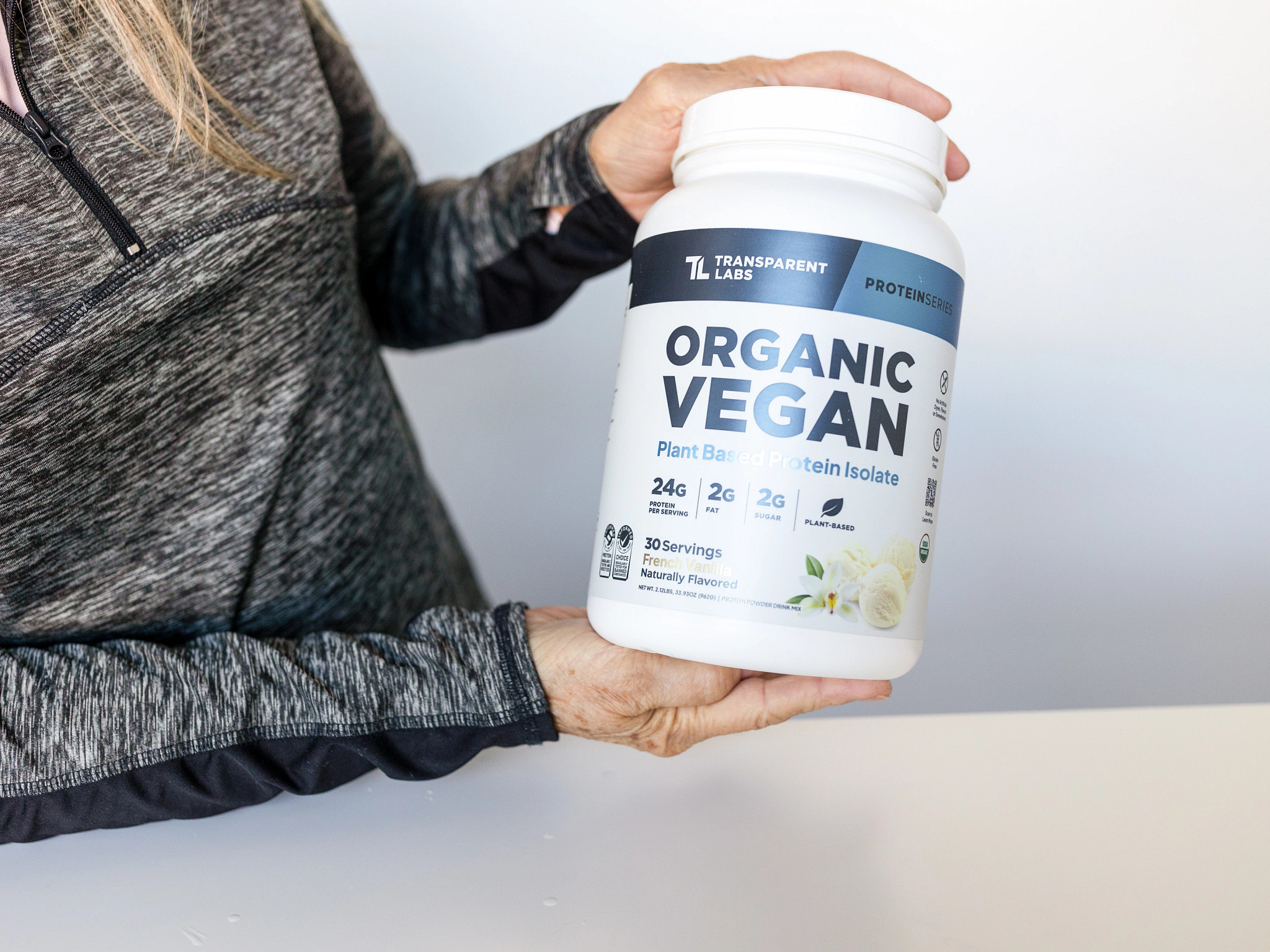 A person holding a container of the Transparent Labs Organic Vegan Plant-Based Protein