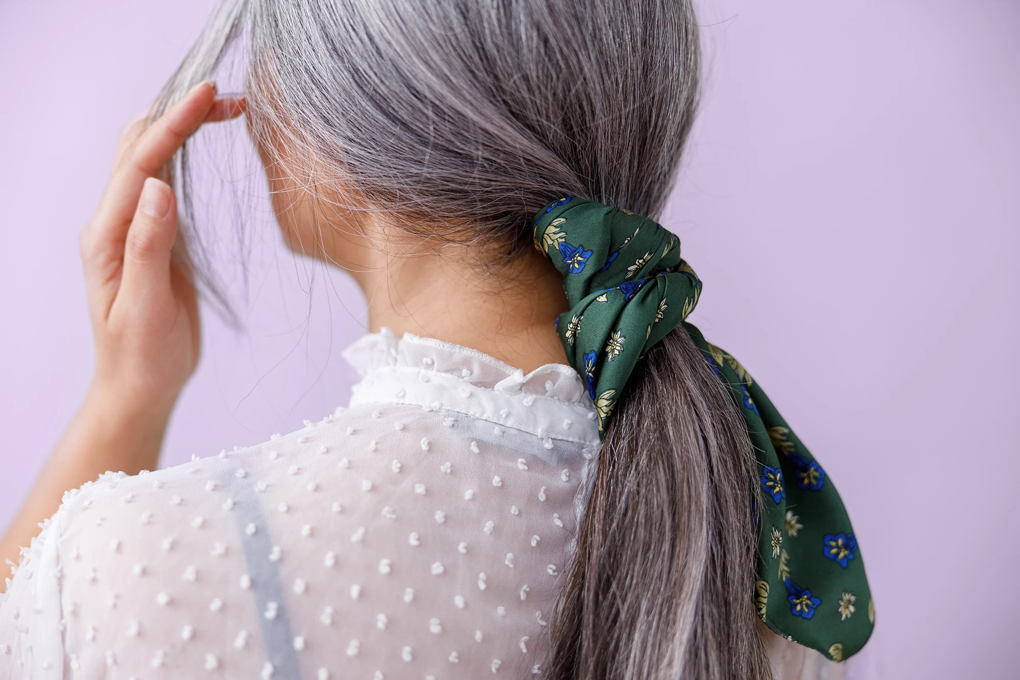 Woman from behind brushing back her beautiful gray hair