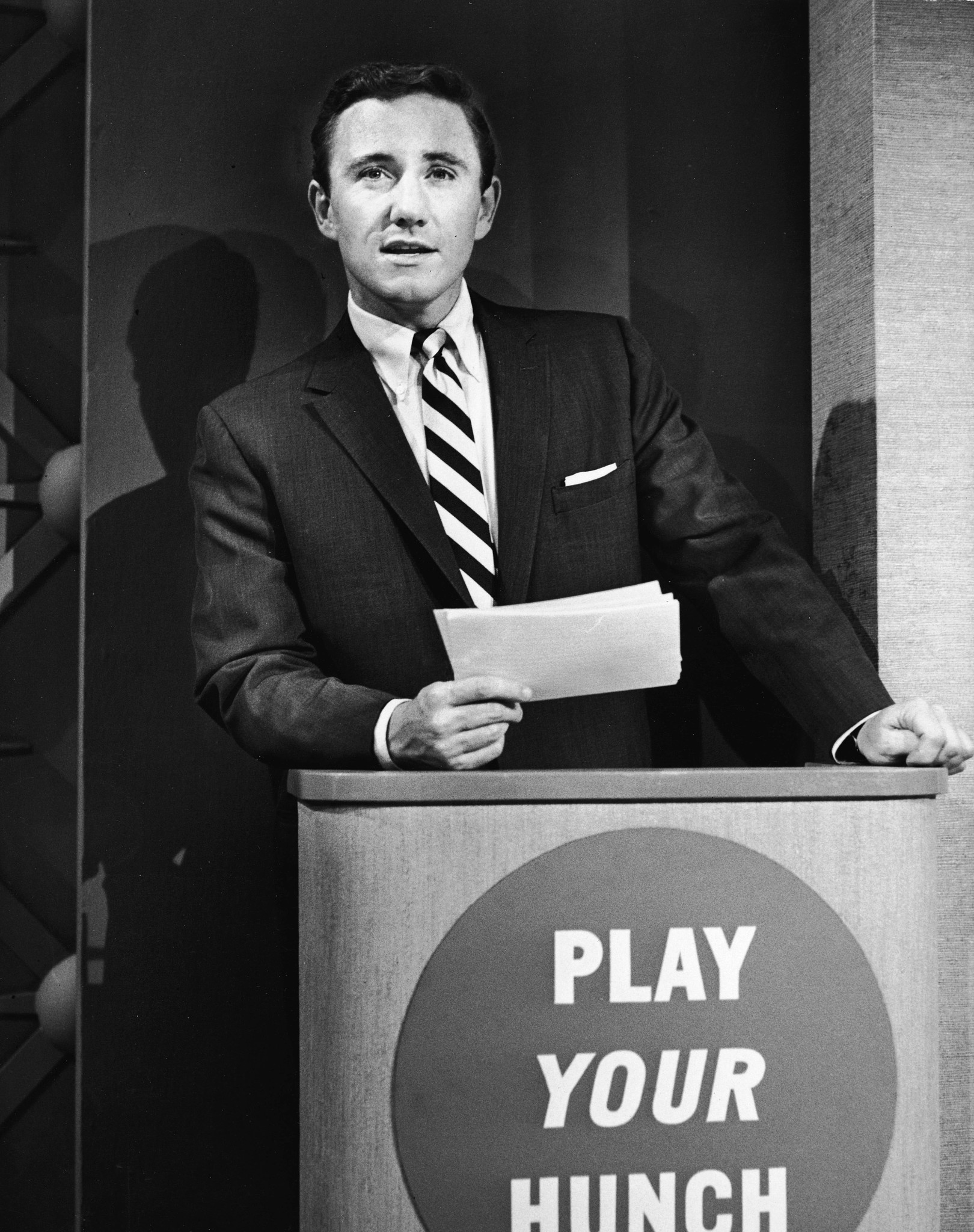 Merv Griffin holding index cards while hosting the game show Play Your Hunch
