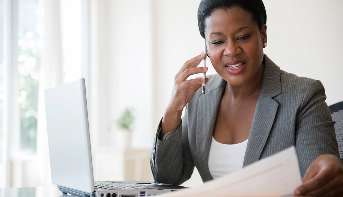 Woman in business clothing looking at resumes and working on her laptop