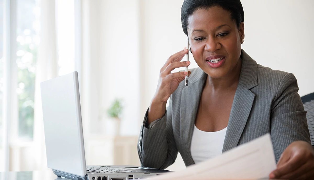 Woman in business clothing looking at resumes and working on her laptop