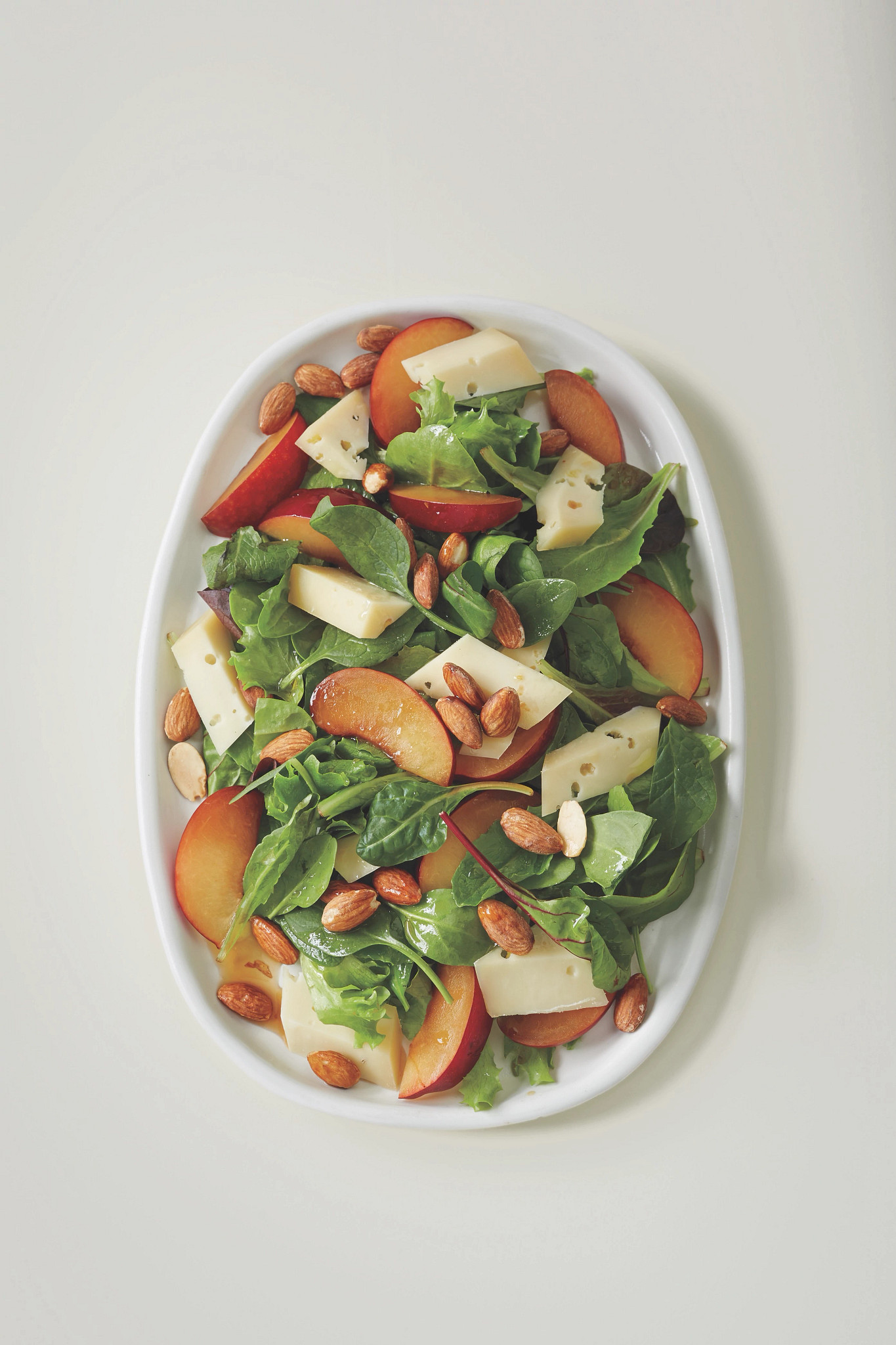 A photo shows Mark Bittman’s light green salad with plums, fontina and almonds