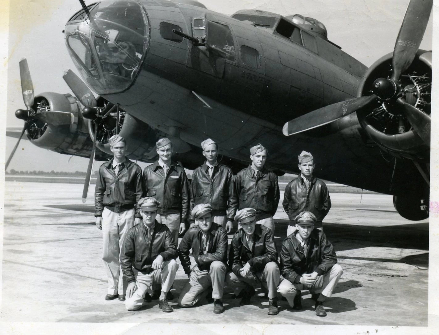 les schrenk posing with his unit in front of a b 17 bomber plane in 1943